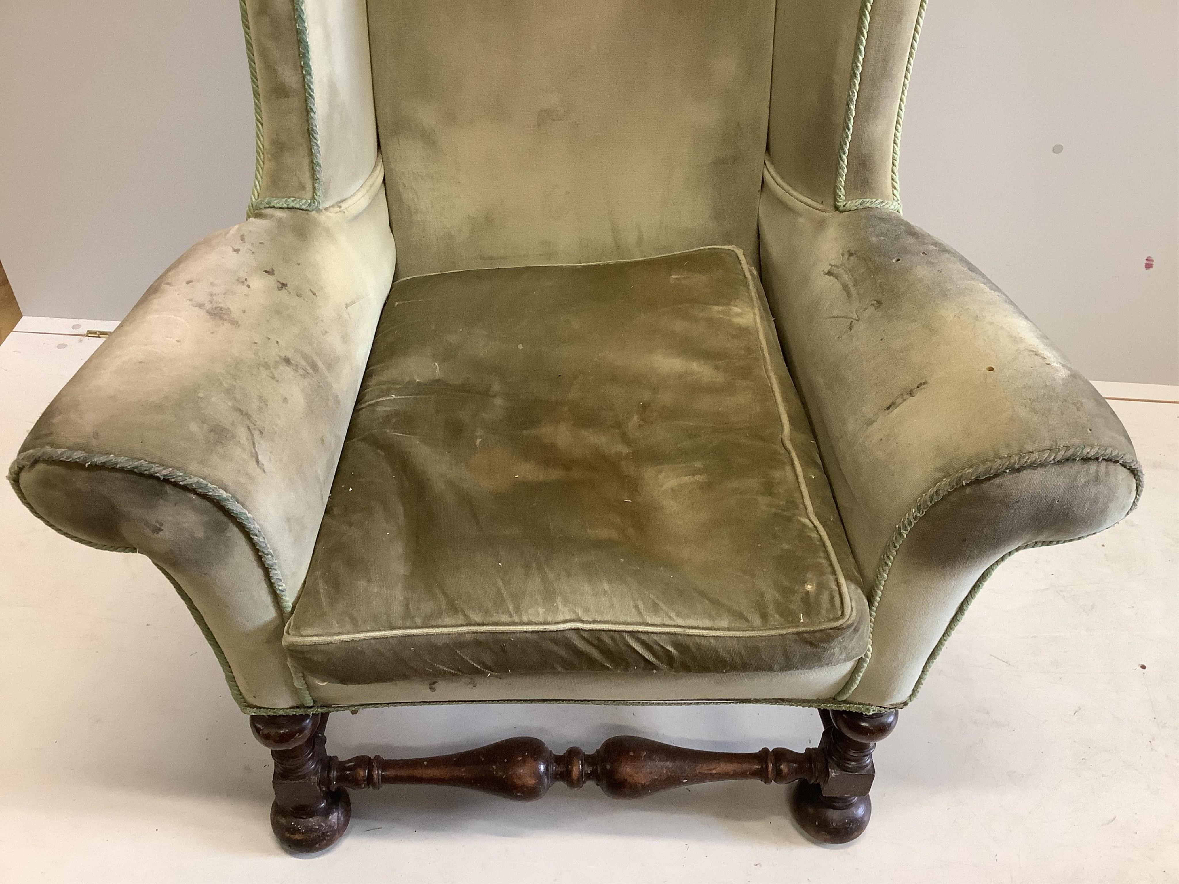 A William and Mary style wing back armchair, upholstered in green dralon, width 68cm, height 136cm. Condition - poor